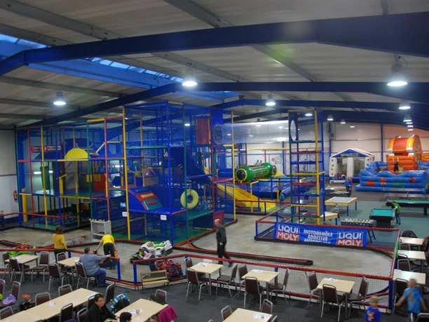 Familien-Hallenspielplatz Sternenland Bunte Kletteranlage und Hüpfburgen in großer Halle mit Spielbereich und Sitzplätzen für Familien