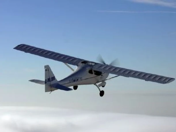Flugschule Dankern Ein einmotoriges Sportflugzeug fliegt über einer Wolkendecke vor blauem Himmel.
