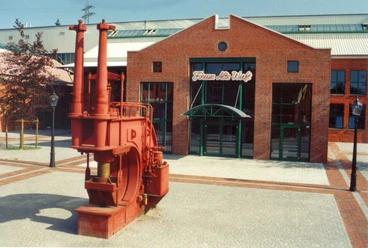 Forum Alte Werft Papenburg Backsteingebäude mit grünem Eingangstor und roter Werftmaschine vor dem Forum Alte Werft Papenburg