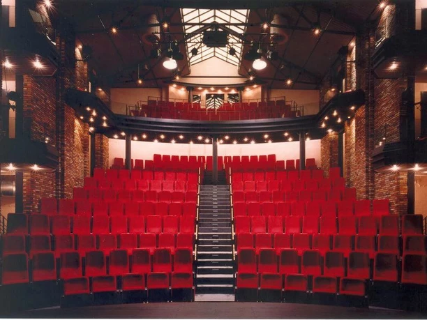 Innenraum der Forum Alte Werft mit roten Theatersitzen, offener Galerie und beleuchteter Bühne.