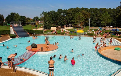 Frei- und Hallenbad Meppen Menschen genießen bei sonnigem Wetter das Freibad Meppen mit Rutsche, Planschbereich und Liegewiese.