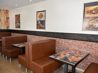Sitzbereich im Kebap-Haus Moderner Sitzbereich mit braunen Polsterbänken und Tischen; Speisenbilder an den hellen Wänden.