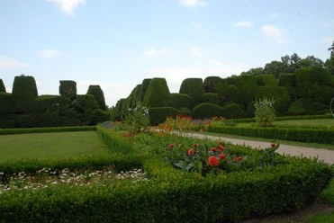 Gartenanlage Gut Altenkamp Gepflegte Gartenanlage mit geometrisch geschnittenen Hecken, Blumenbeeten und breiten Wegen.