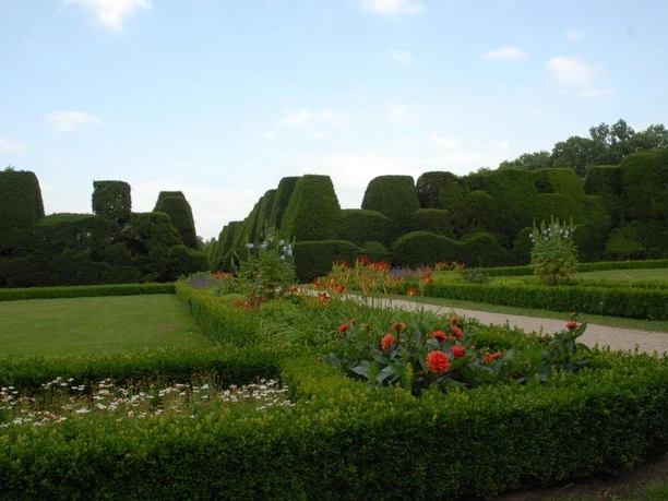 Gartenanlage Gut Altenkamp Gepflegte Gartenanlage mit geometrisch geschnittenen Hecken, Blumenbeeten und breiten Wegen.