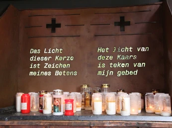 Gebetsstätte Heede Kerzenaltar mit brennenden Gebetslichtern und zweisprachiger Inschrift in der Gebetsstätte Heede