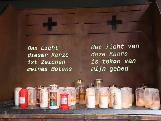 Gebetsstätte Heede Kerzenaltar mit brennenden Gebetslichtern und zweisprachiger Inschrift in der Gebetsstätte Heede