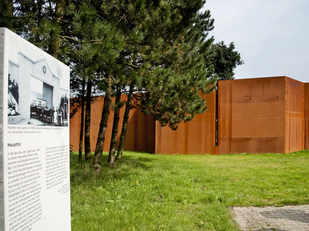 Gedenkstätte Esterwegen Edelrostfarbene Stahlwand mit Informationstafel zur Geschichte der Gedenkstätte Esterwegen im Grünen