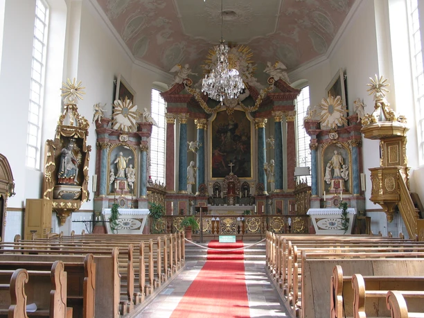 Gymnasialkirche und Residenz Barockes Kircheninnere mit reich verziertem Altar, Kanzel, Statuen und rotem Teppichgang.
