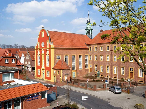 Gymnasialkirche und Residenz Barocke Kirche mit rotem Giebel und gelben Säulen, daneben die historische Residenz in Meppen.