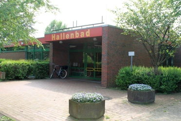 Hallenbad Twist Eingang des Hallenbads Twist mit roter Beschilderung, Backsteinfassade und grüner Glastür.