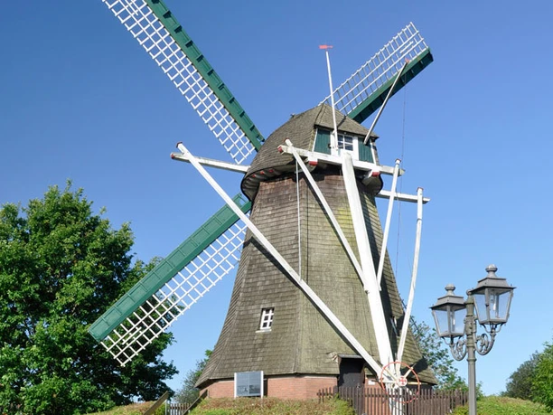 Haren Mersmühle Historische Windmühle in Haren mit grünen Flügeln, rotem Dach und blauem Himmel im Hintergrund.