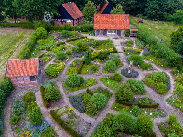 Heilkräutergarten Emsbüren Luftaufnahme eines Heilkräutergartens mit verschlungenen Wegen, Beeten und Fachwerkhäusern im Grünen