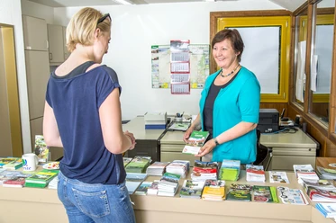 Touristikbüro der Gemeinde Geeste Mitarbeiterin berät Besucherin am Informationstresen des Touristikbüros Geeste mit Flyern und Karten