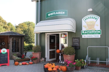 Kartoffelhof und Hofladen Anneken Eingang eines Hofladens mit Kürbissen, Blumen und einem Schild für Kartoffeln aus eigenem Anbau