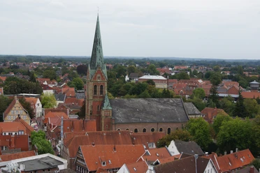 St.-Bonifatius-Kirche in Lingen Backsteinkirche mit hohem grünen Turm, umgeben von roten Dächern im Stadtzentrum von Lingen.