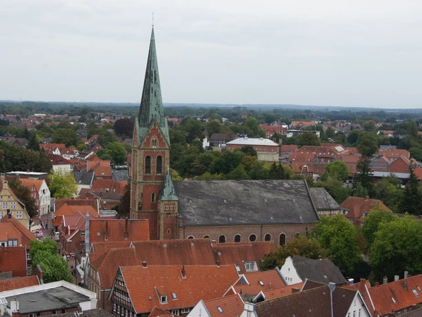 St.-Bonifatius-Kirche in Lingen Backsteinkirche mit hohem grünen Turm, umgeben von roten Dächern im Stadtzentrum von Lingen.