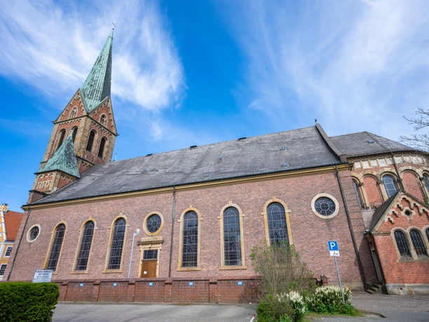 St.-Bonifatius-Kirche in Lingen Backsteinkirche mit hohem Turm und grüner Spitze unter blauem Himmel in der Innenstadt von Lingen