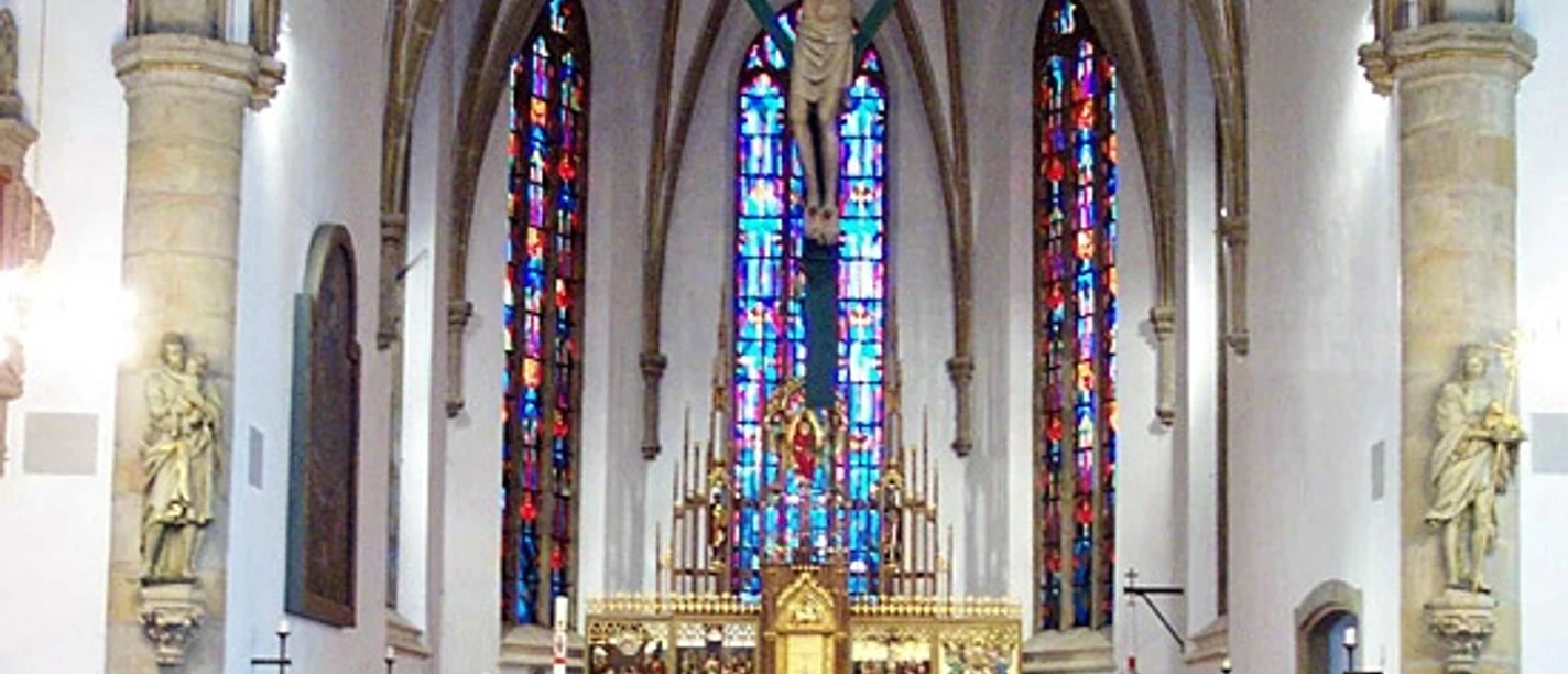 St.-Vincentius-Kirche Innenraum der St.-Vincentius-Kirche mit Altar, Kreuzigungsgruppe und farbigen Glasfenstern.