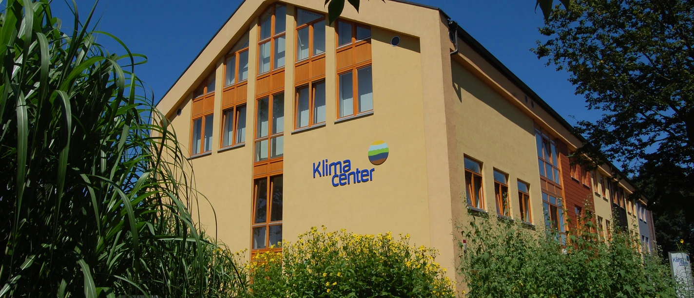 Klimacenter Werlte Modernes Gebäude des Klimacenters Werlte mit gelber Fassade, großen Fenstern und grüner Bepflanzung.