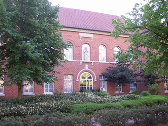 Backsteingebäude des Ludmillenstifts Meppen mit Rundbogenfenstern und grünem Vorgarten.
