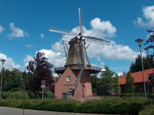 Kreutzmanns Mühle Historische Windmühle mit rotem Backsteinsockel und Holzflügeln vor blauem Himmel in Werlte.