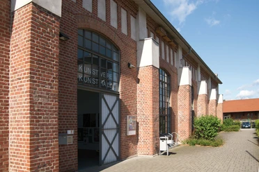 Kunsthalle Lingen Backsteingebäude mit großen Rundbogenfenstern und geöffnetem Eingangstor zur Kunsthalle Lingen