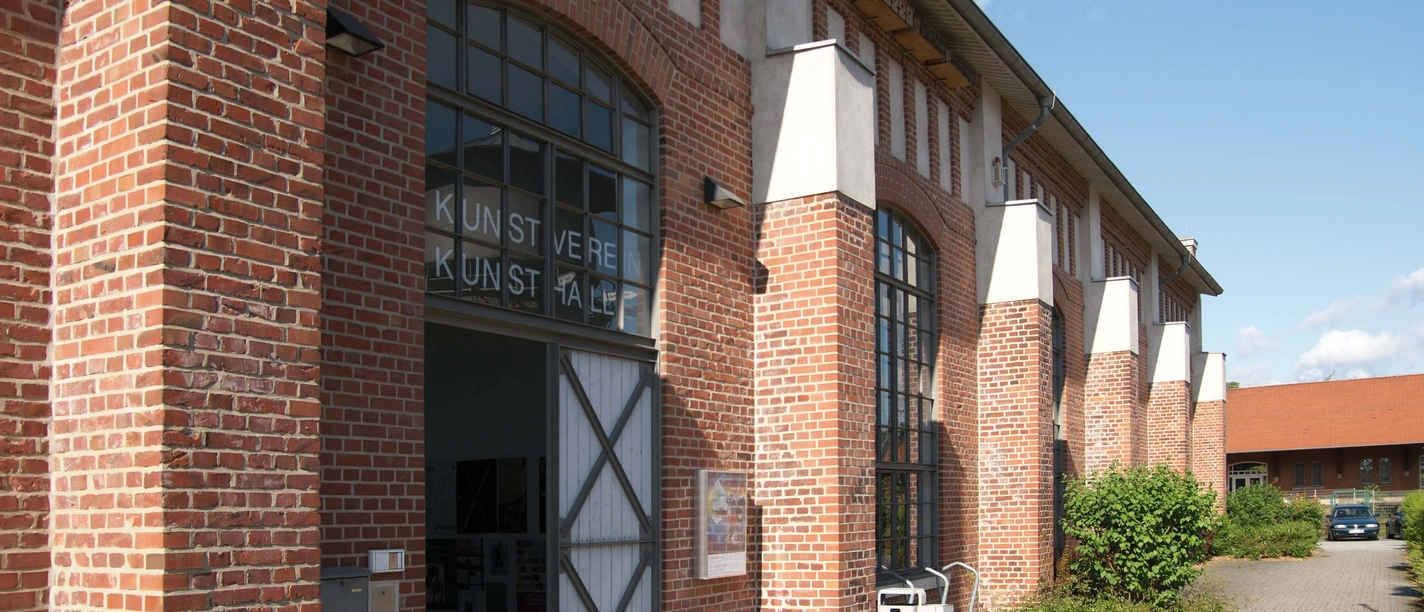 Kunsthalle Lingen Backsteingebäude mit großen Rundbogenfenstern und geöffnetem Eingangstor zur Kunsthalle Lingen