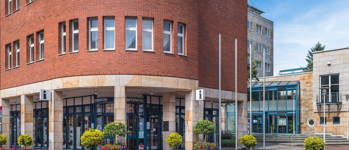 Lingen Wirtschaft + Tourismus GmbH Moderne Touristeninformation in rotem Klinkerbau mit Glasfront und bunten Blumenkübeln davor