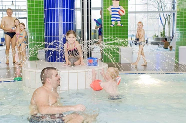 Linus Lingen Wasserwelten Kinder planschen fröhlich im warmen Hallenbecken mit Wasserfontänen in den Linus Lingen Wasserwelten.