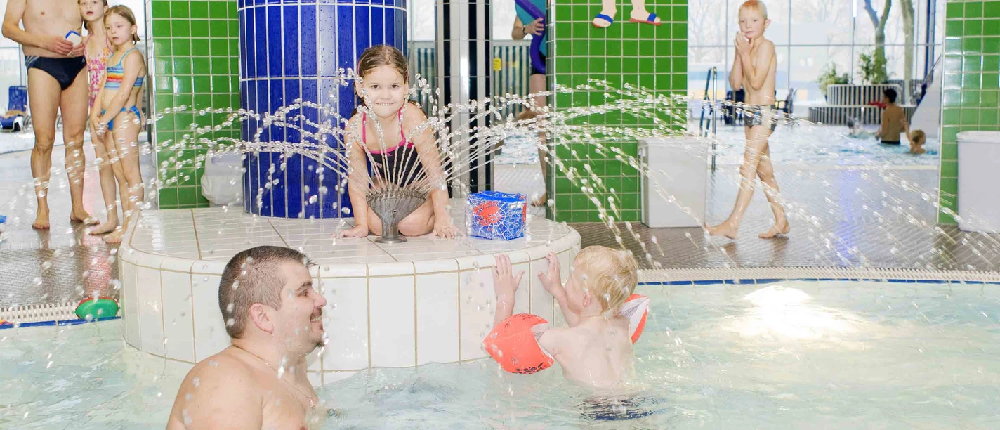 Linus Lingen Wasserwelten Kinder planschen fröhlich im warmen Hallenbecken mit Wasserfontänen in den Linus Lingen Wasserwelten.
