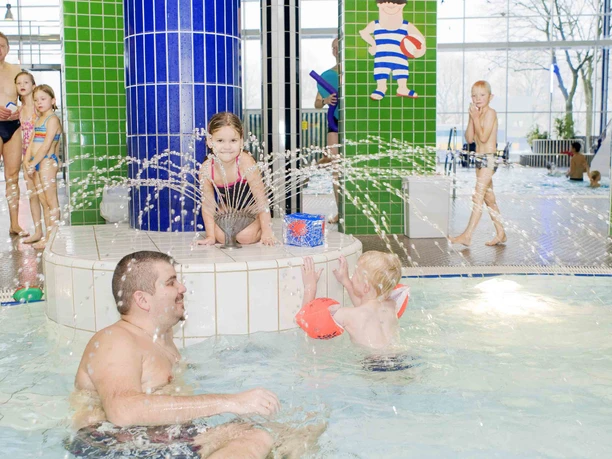 Linus Lingen Wasserwelten Kinder planschen fröhlich im warmen Hallenbecken mit Wasserfontänen in den Linus Lingen Wasserwelten.