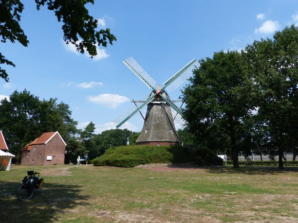 Mersmühle (mit Mühlenmuseum Haren) Historische Windmühle mit Flügeln aus Holz, umgeben von Bäumen und roten Backsteinhäusern.