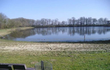 Naturbad an der Borsumer Straße Kleiner Badesee mit Sandufer, klarer Wasserfläche und Bäumen im Hintergrund unter blauem Himmel.