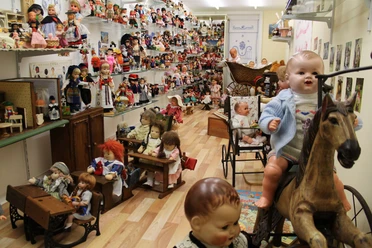 Uli's Puppenstube im Bürgerhaus Alte Schule Raum mit zahlreichen historischen Puppen, Puppenwagen und Spielzeug aus verschiedenen Epochen.