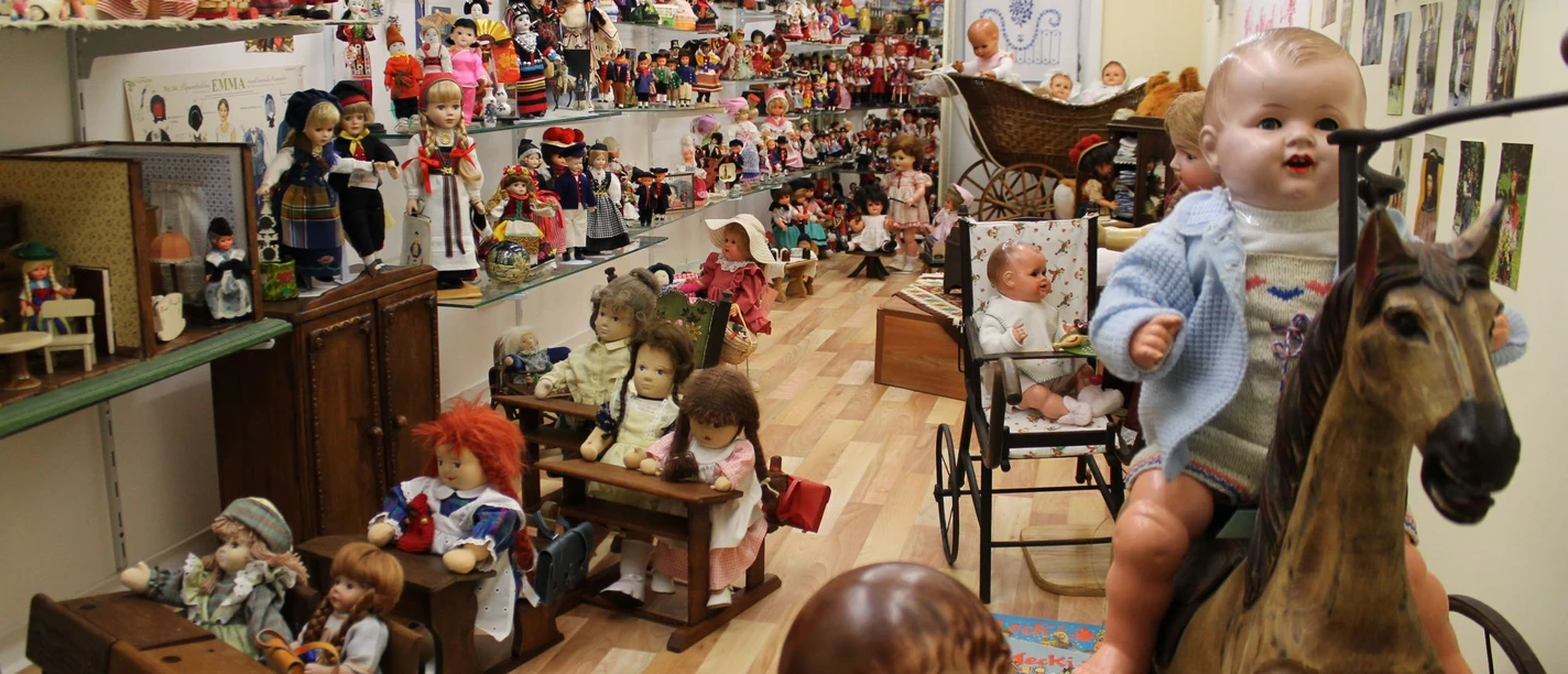 Uli's Puppenstube im Bürgerhaus Alte Schule Raum mit zahlreichen historischen Puppen, Puppenwagen und Spielzeug aus verschiedenen Epochen.