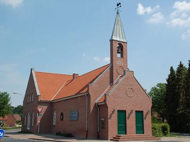 Lathen Backsteingebäude mit rotem Ziegeldach und kleinem Glockenturm unter blauem Himmel in Lathen