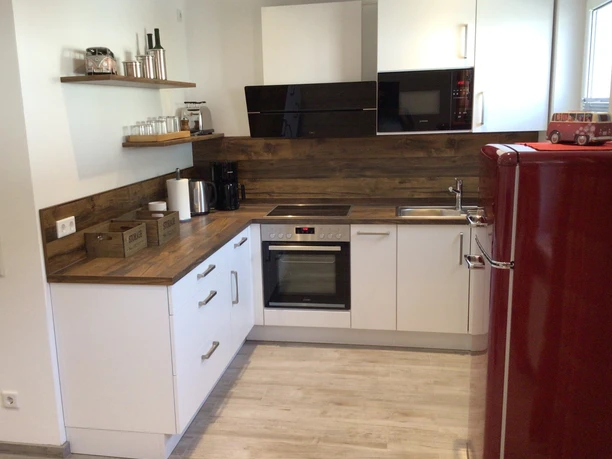 Moderne Küche mit Holz-Akzenten, ausgestattet mit roten Retro-Kühlschrank und weißen Schrankfronten.