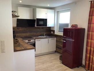 Moderne Küche mit Holzarbeitsplatten, roter Retro-Kühlschrank, Backofen, Mikrowelle und Spüle.