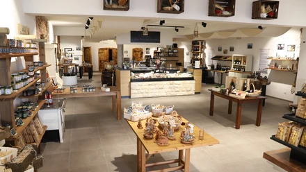 Degrassi gourmet - Tradition trifft Moderne Moderner Verkaufsraum mit traditionellen Produkten, Holztischen und Regalen voller lokaler Köstlichkeiten.