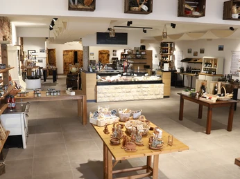 Degrassi gourmet - Tradition trifft Moderne Moderner Verkaufsraum mit traditionellen Produkten, Holztischen und Regalen voller lokaler Köstlichkeiten.