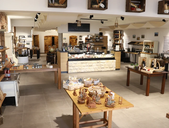 Degrassi gourmet - Tradition trifft Moderne Moderner Verkaufsraum mit traditionellen Produkten, Holztischen und Regalen voller lokaler Köstlichkeiten.