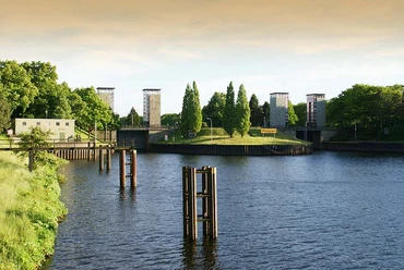Schleuse Meppen Wasserweg mit Schleusenanlage in grüner Umgebung, moderne Türme und Bäume im Hintergrund.