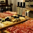 Italienische Antipasti-Platten mit Aufschnitt, Käse und Oliven, begleitet von Weißwein auf Holztafeln.