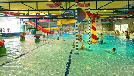 Spaßbad Topas Buntes Hallenbad mit Rutschen, Wasserspielen und fröhlichen Badegästen in lebendiger Atmosphäre