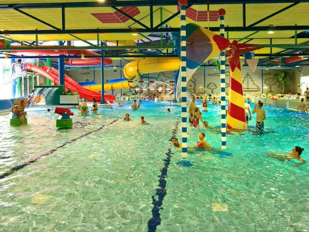 Spaßbad Topas Buntes Hallenbad mit Rutschen, Wasserspielen und fröhlichen Badegästen in lebendiger Atmosphäre