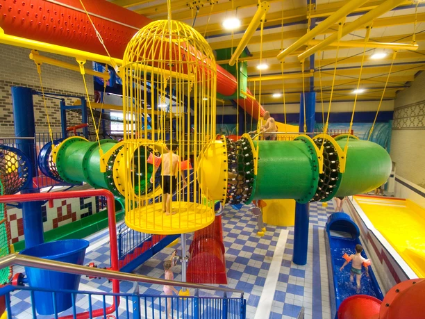 Spaßbad Topas Buntes Indoor-Wasserparadies mit Röhrenrutschen, Kletterelementen und spielenden Kindern im Becken