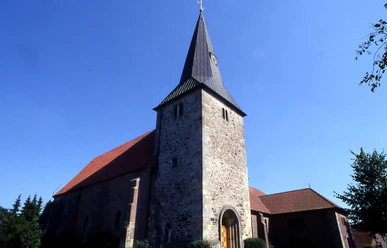 St.-Nikolaus-Kirche in Groß Hesepe Steinkirche mit hohem Turm und spitzem Dach vor blauem Himmel in Groß Hesepe.