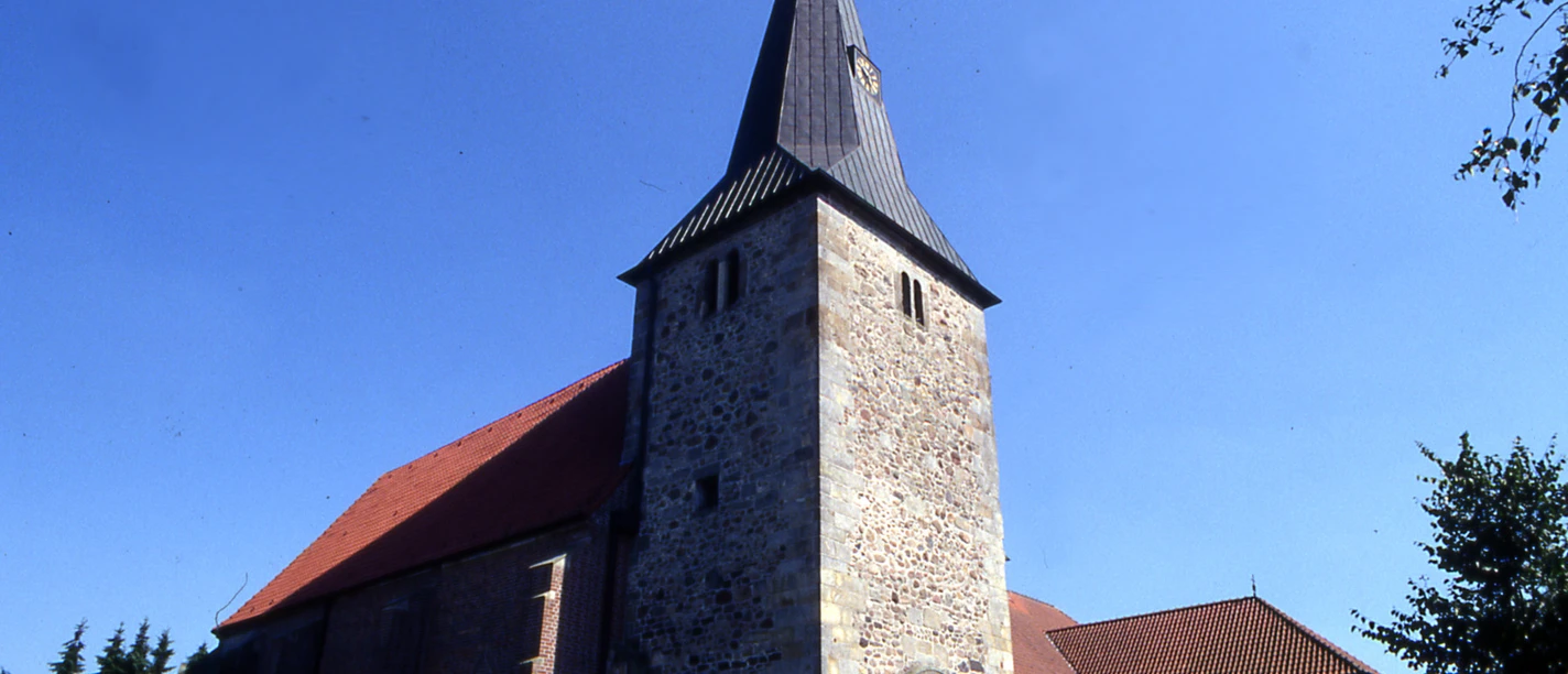 St.-Nikolaus-Kirche in Groß Hesepe Steinkirche mit hohem Turm und spitzem Dach vor blauem Himmel in Groß Hesepe.