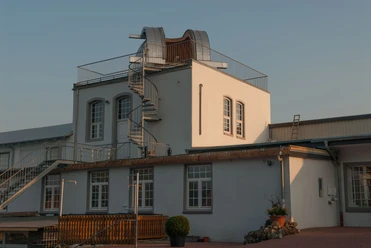 Sternwarte Papenburg Zweigeschossiges Gebäude mit weißer Fassade, Dachkuppel und Wendeltreppe der Sternwarte Papenburg.