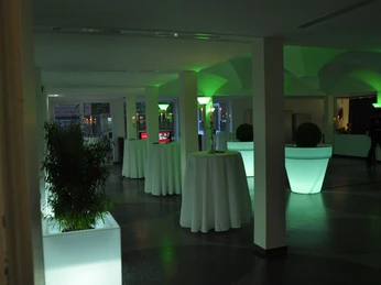 Beleuchteter Empfangsraum im Theater Meppen mit hohen Stehtischen und grüner Lichtgestaltung.